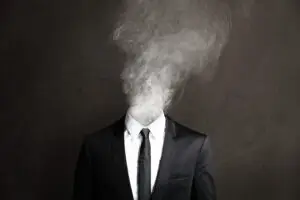 Concept image of executive burnout showing a businessperson in suit with head replaced by smoke, symbolizing stress, exhaustion, and lack of clarity.