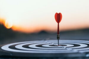 Red dart hitting exact center of bullseye target at sunset representing leadership focus and strategic precision