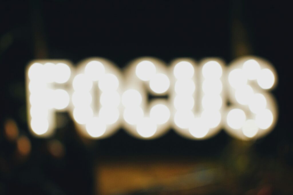 Blurred illuminated letters spelling FOCUS in glowing marquee lights representing leadership concentration and clarity