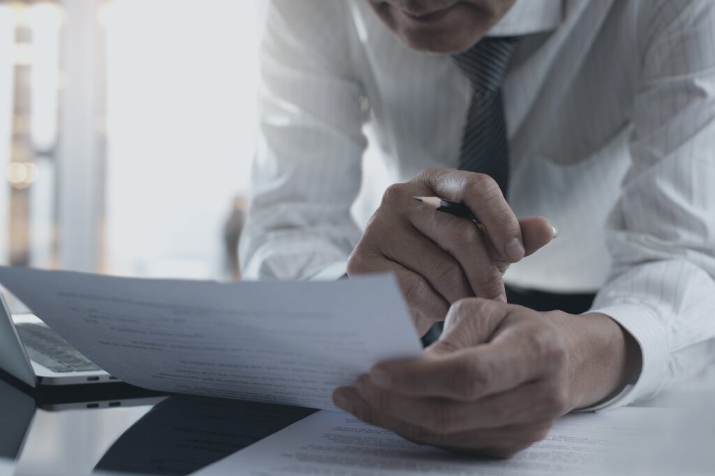 A business leader reading one document closely, pen in hand, the judgment that cuts through workslop.